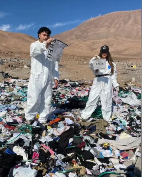 Personas pisando la monta&ntilde;a de ropa usada con bolsas de Shein en sus manos